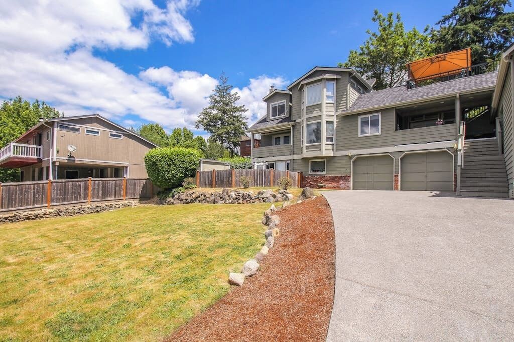 A residential area with two houses, a driveway, and a well-maintained lawn.