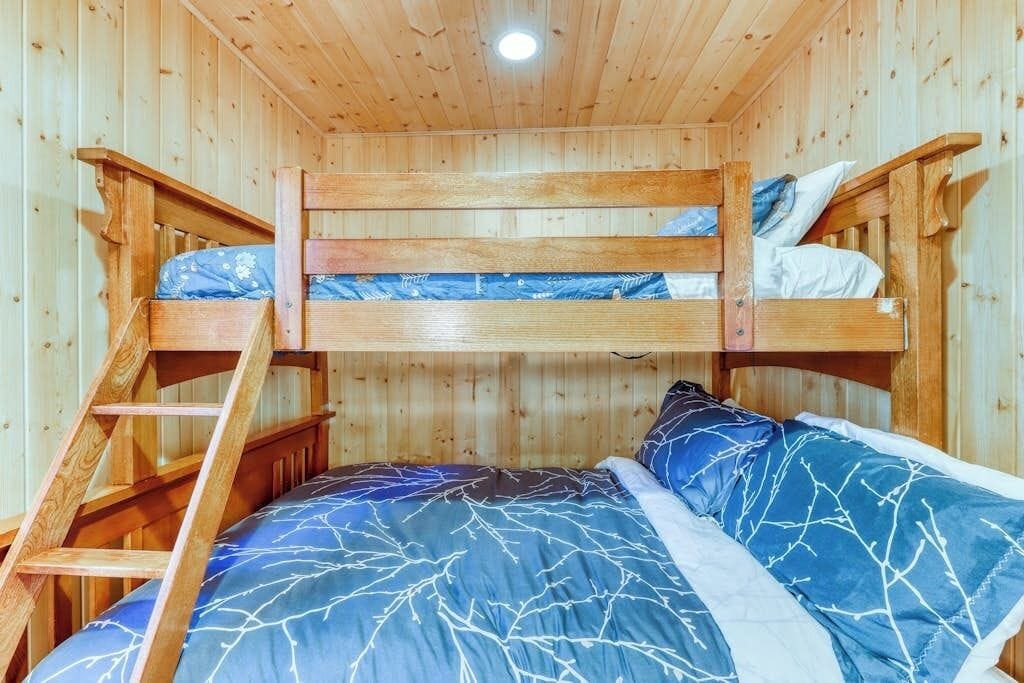 Habitación con literas, una escalera, paredes de madera y una luz en el techo.
