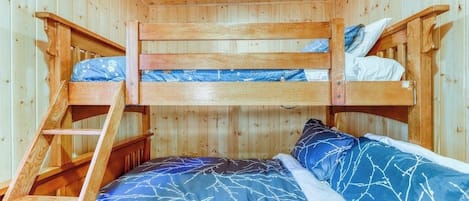 Habitación con literas, una escalera, paredes de madera y una luz en el techo.