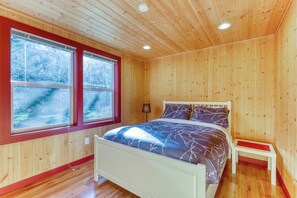 A wooden-paneled room with a bed, two windows, and a nightstand. - 4BR Mountainview Dog Friendly - Hot Tub - Deck (Skykomish)