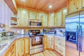 Eine Küche mit Holzausstattung, Edelstahlgeräten und einer Arbeitsplatte aus Granit.