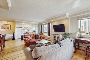 A living room with a sofa, a coffee table, a TV, and a dining area with chairs and a table. - Downtown 1BR Washington State Conv. Center 14th-fl (Seattle)