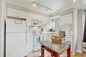 A kitchen with white cabinets, a microwave, a stove, and a coffee maker. - Downtown 1BR Washington State Conv. Center 14th-fl (Seattle)