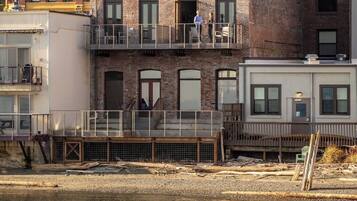 A multi-story building with a brick facade, a balcony, and a waterfront view.