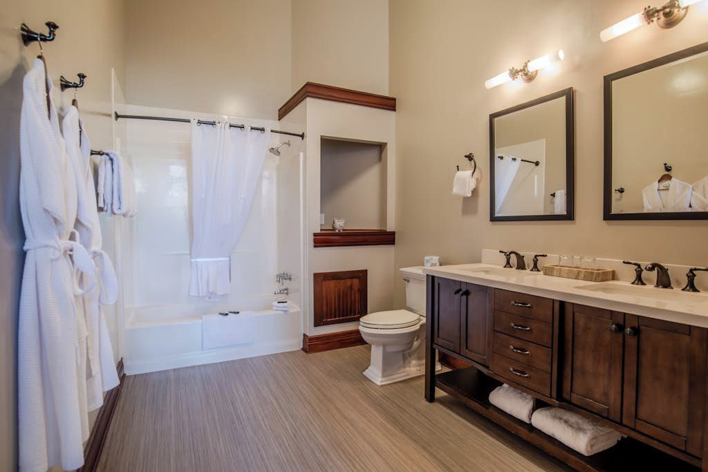 A bathroom with a bathtub, toilet, vanity with drawers, and a mirror.