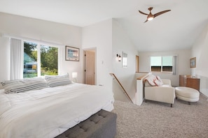 A bedroom with a bed, a chair, a desk, and a ceiling fan.