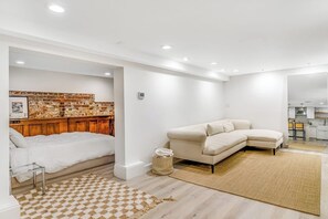 A modern living room with a sofa, a patterned rug, and a brick accent wall. - Modern Studio - 1st Floor - 1 Block to Kerry Park (Seattle)
