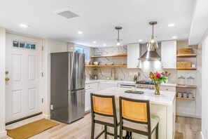 A modern kitchen with a stainless steel refrigerator, wooden chairs, a marble countertop, and pendant lighting. - Modern Studio - 1st Floor - 1 Block to Kerry Park (Seattle)