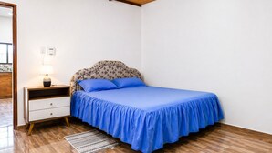 Ein Schlafzimmer mit einem Bett, einem Nachttisch, einer Lampe und einem Teppich.