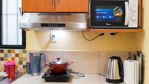 A kitchen with wooden cabinets, a microwave, a stove, and various kitchen utensils.
