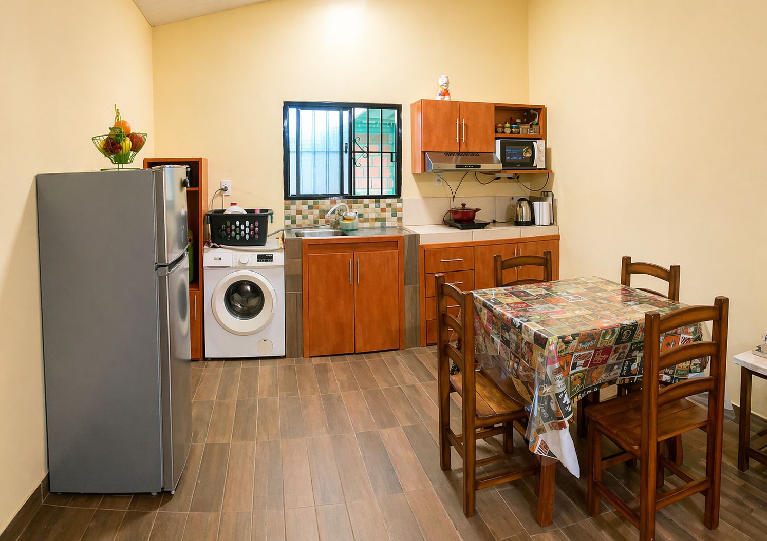 Una cocina compacta con refrigerador, lavadora, microondas y armarios de madera.