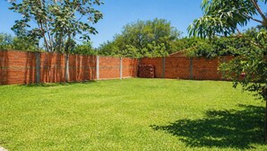A well-maintained backyard with a brick wall, a grassy lawn, and trees.