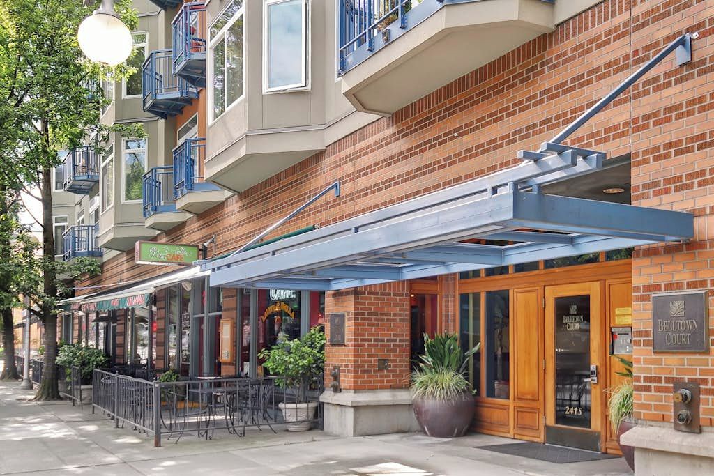 A multi-story building with a brick facade, outdoor seating area, and a sign for 'Belltown Court.'