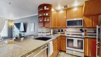A modern kitchen with granite countertops, wooden cabinets, stainless steel appliances, and a built-in microwave.