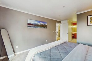 Ein Schlafzimmer mit einem Bett, einem Gemälde und einer Tür zu einem Badezimmer.