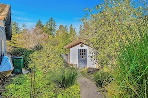 A small white building with a brown roof, surrounded by dense greenery and a clear blue sky. - 3BR waterfront home, private hot tub and game room (Gig Harbor)