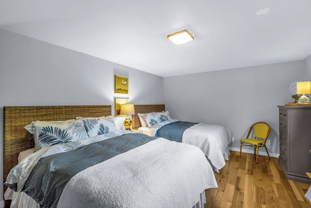 Et hotelværelse med to senge, et trægavl, et lille skrivebord med stol, et skab og en loftslampe.