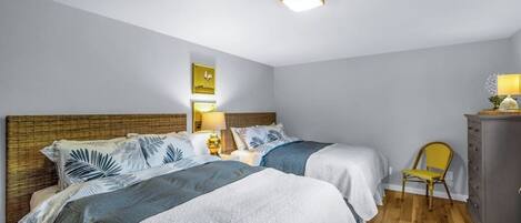 Et hotelværelse med to senge, et trægavl, et lille skrivebord med stol, et skab og en loftslampe.