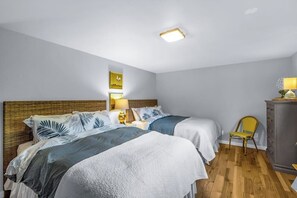 A hotel room with two beds, a wooden headboard, a small desk with a chair, a cabinet, and a ceiling light fixture. - 3BR waterfront home, private hot tub and game room (Gig Harbor)