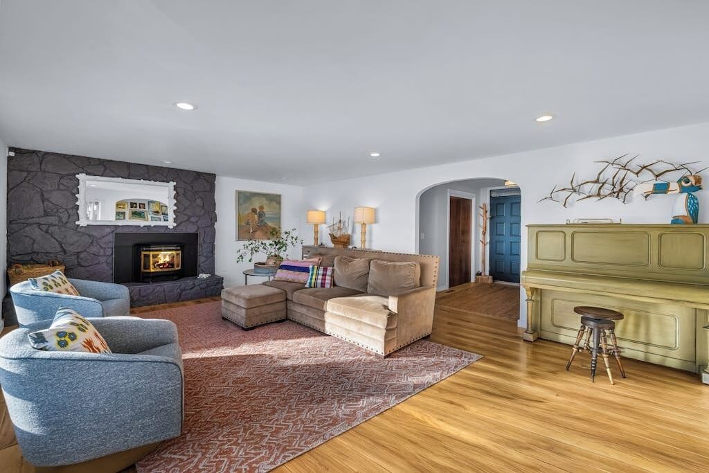 A living room with a fireplace, a sofa, a coffee table, and a piano.