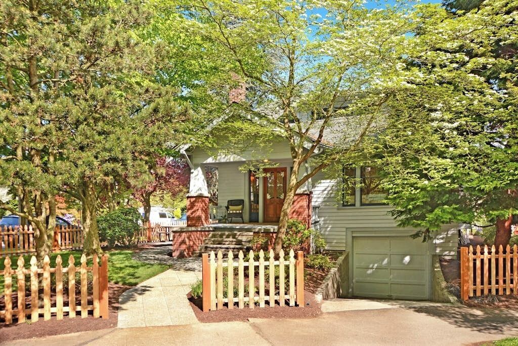 Ein Wohnhaus mit Veranda, Garage und einem Zaun aus Brettern.