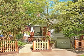 Et hus med veranda, garage og et stakhegn.