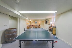 A ping pong table in a room with a sofa set, a wooden barrel, and a cabinet with a lamp. - Lovely 4BR Lakeview - Game Room - Foosball (Seattle)