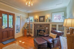 A cozy living room with a fireplace, leather sofa, and a wooden door with stained glass. - Lovely 4BR Lakeview - Game Room - Foosball (Seattle)