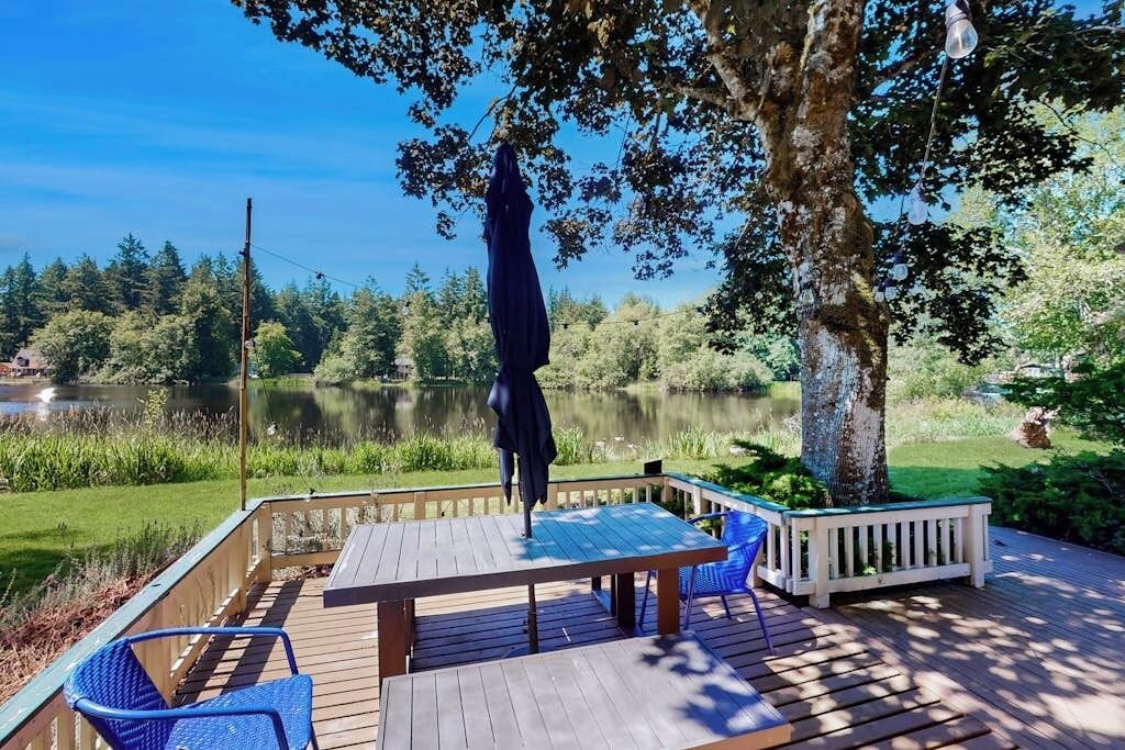 Une terrasse en bois avec une table et des chaises, donnant sur un lac.