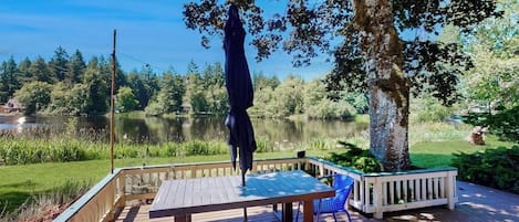 Une terrasse en bois avec une table et des chaises, donnant sur un lac.
