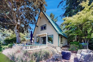 A single-story house with a gabled roof, a porch with outdoor seating, and a deck area. - 3BR waterfront home with gas grill and deck (Lacey)