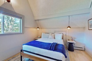 Ein Schlafzimmer mit einem Bett, Nachttischen, einem Fenster und einem Deckenventilator.