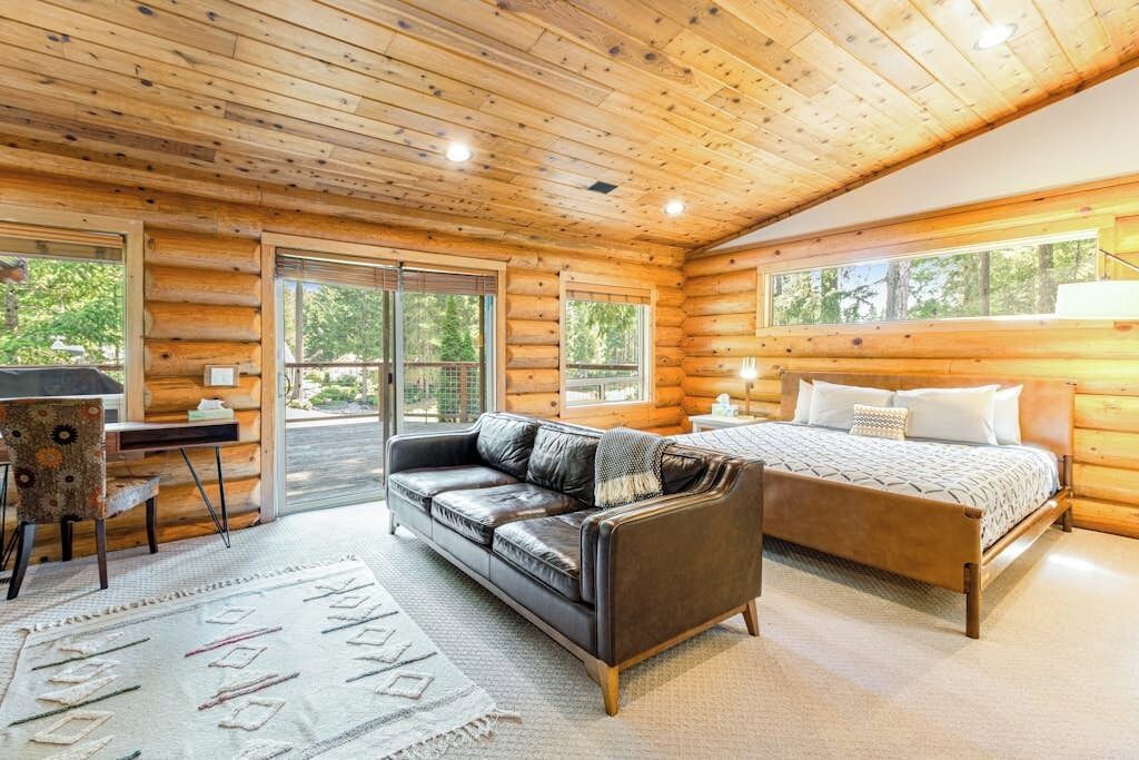 Een slaapkamer in een blokhut met een bed, een leren bank, een bureau en een stoel.