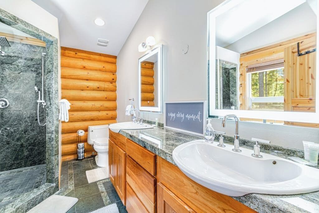 A bathroom with a wooden wall, a large mirror, a sink, and a shower.