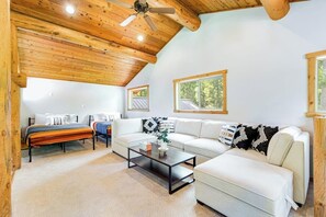 A spacious living area with a high ceiling, wooden beams, a sofa set, a coffee table, and a bed with a striped blanket. - Custom 3BR Golf Course View - Chef's Kitchen (Union)