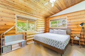A log cabin bedroom with a bed, a bench, and two windows. - Custom 3BR Golf Course View - Chef's Kitchen (Union)