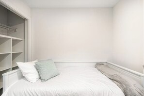 A bedroom with a bed, white walls, and a white radiator. - Corner 3BR - Balcony - Street Parking - Washer Dryer (Seattle)