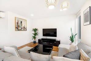 Un salon moderne avec un téléviseur à écran plat, une table basse et deux canapés.