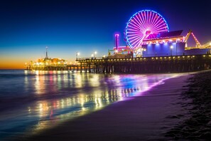 A pier with a large Ferris wheel and a building with lights.