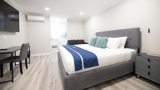 Un dormitorio moderno con una cama grande, mesitas de noche, un escritorio y un televisor de pantalla plana.