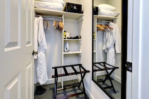 A walk-in closet with hanging clothes, shelves, and a mirror.
