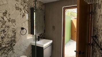 Un baño con inodoro, lavamanos y zona de ducha.