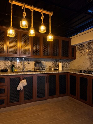 A kitchen with wooden cabinets, a marble backsplash, and pendant lights.