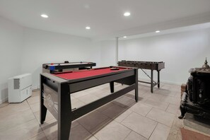 Une pièce équipée d’une table de billard, d’un baby-foot et d’un grand climatiseur.