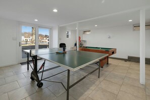 A room with a ping pong table, a pool table, and a view through a glass door. - Dog Friendly Lakeview Family Retreat with Hot Tub, Firepit and Game Room (Jefferson)