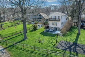 Une maison à deux étages avec un patio, une cour clôturée et des arbres.