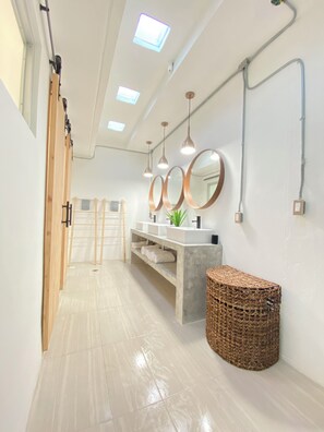 Une salle de bain moderne avec un meuble-lavabo, des miroirs et un panier en osier.