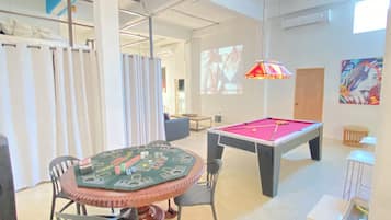 Une table de billard équipée, avec ses billes, une queue de billard et un drap de table.