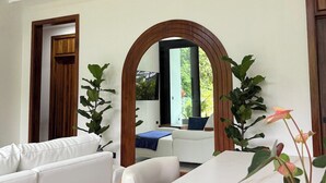 Un interno moderno con un divano bianco, un arco in legno e una pianta in vaso.