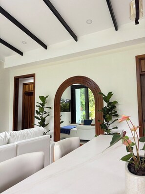 Een modern interieur met een witte zithoek, een boogvormige boogpartij met houten frame en een potplant.
